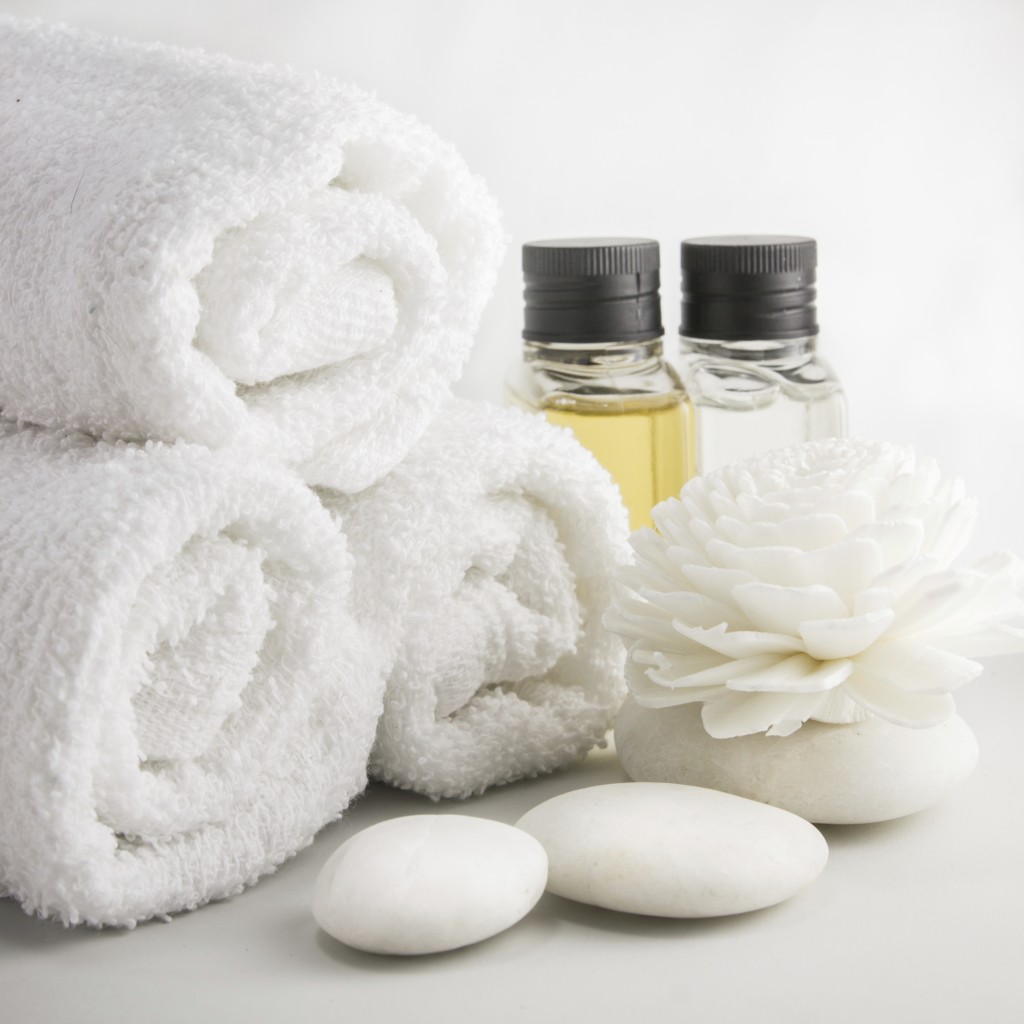 Spa setting with towels aroma oil bottles and hand made flower.