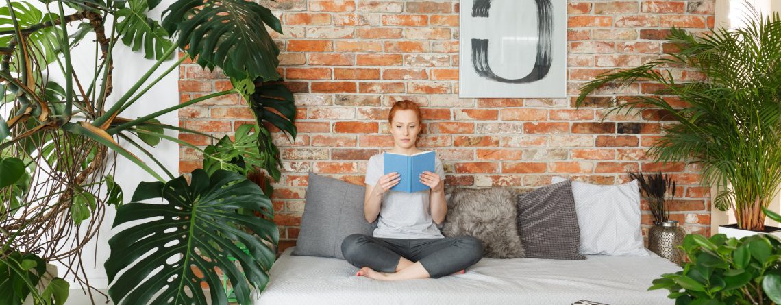 Young woman reading book in stylish contemporary apartment