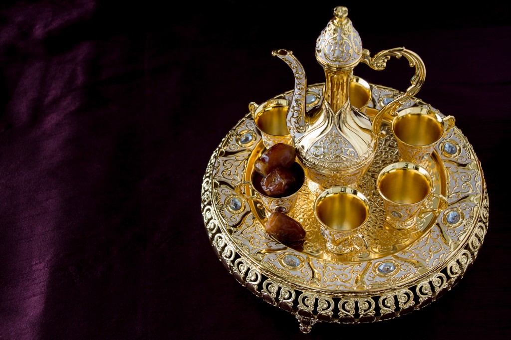 Traditional golden arabic coffee set with dallah, two cups and dates. Dark background. 