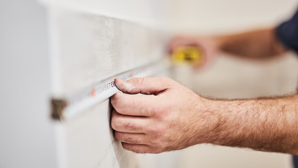 man measuring wall with tape measure