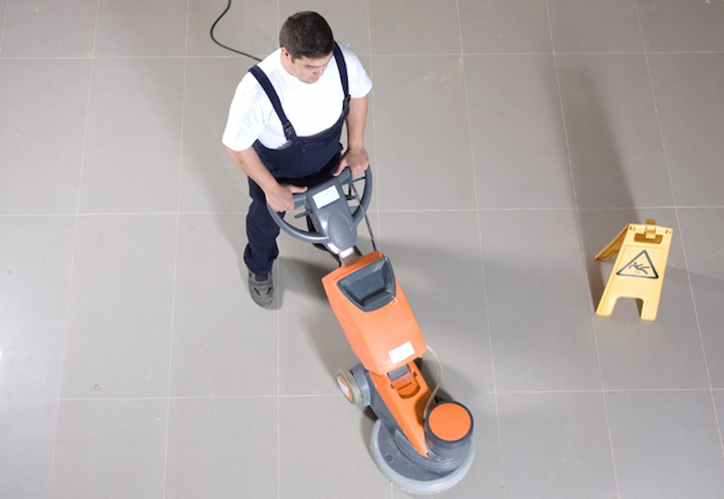 A person on a cleaning tiled flooring with a machine cleaner