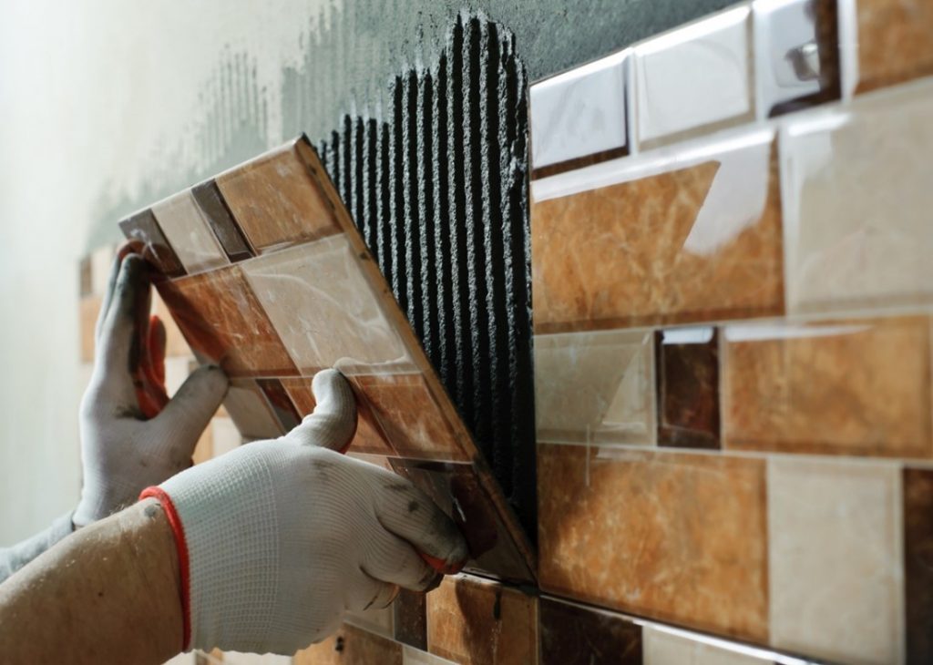 A person installing a tile on a wall