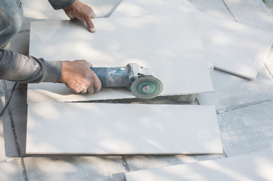 A person using a grinder to cut tile